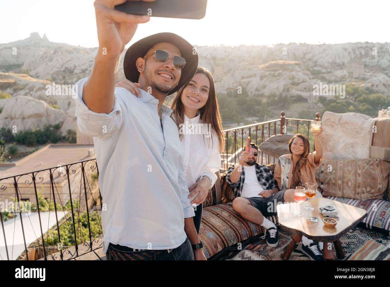 Group of young diverse friends taking selfie on cellphone while drinking cocktails on terrace bar in Cappadocia, Turkey Stock Photo