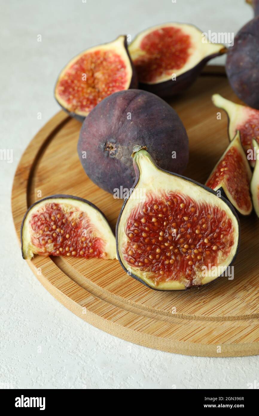 Wooden board with fig on white textured table Stock Photo - Alamy