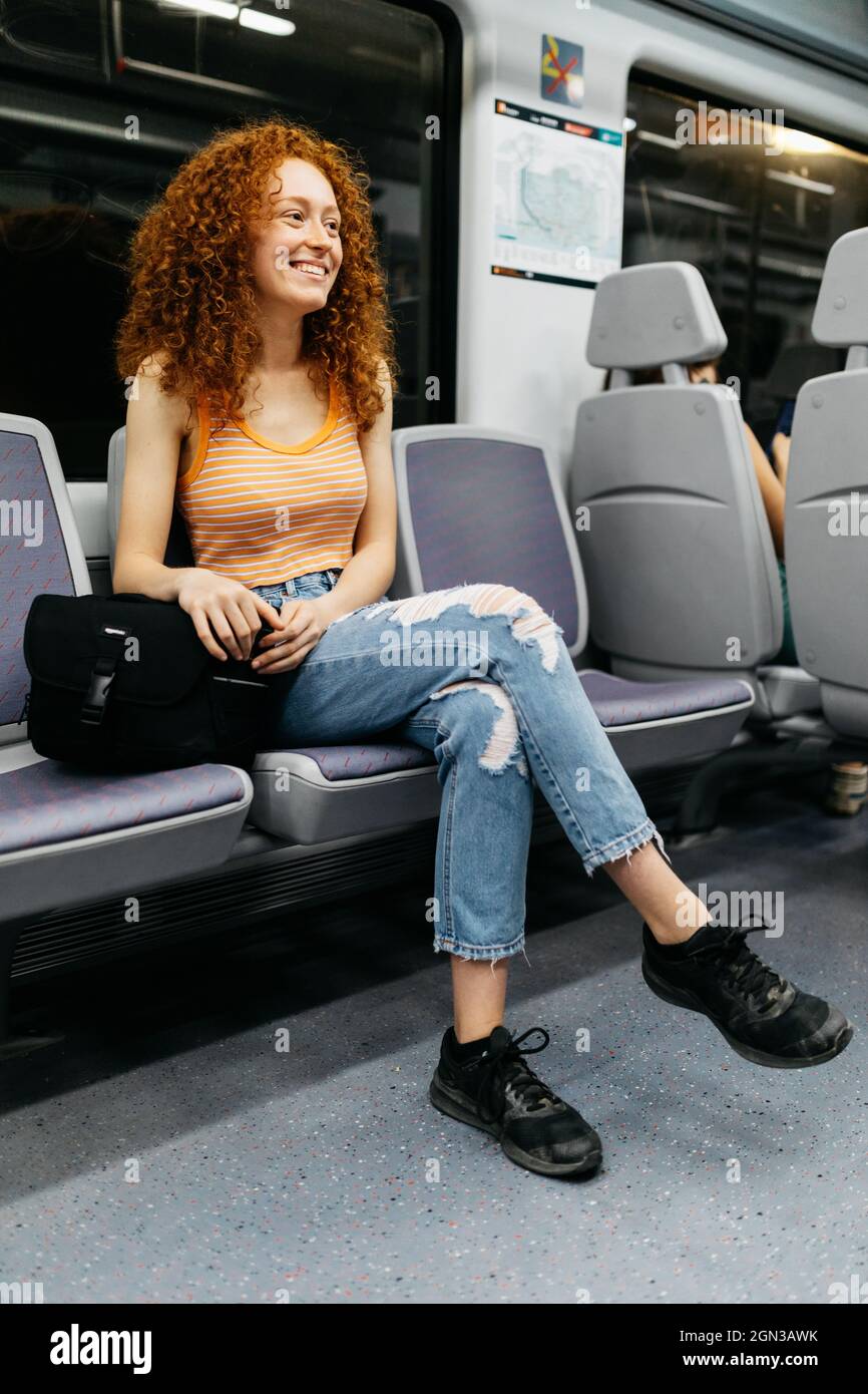 Content young Woman in ripped jeans with curly red hair travelling by train  Stock Photo - Alamy