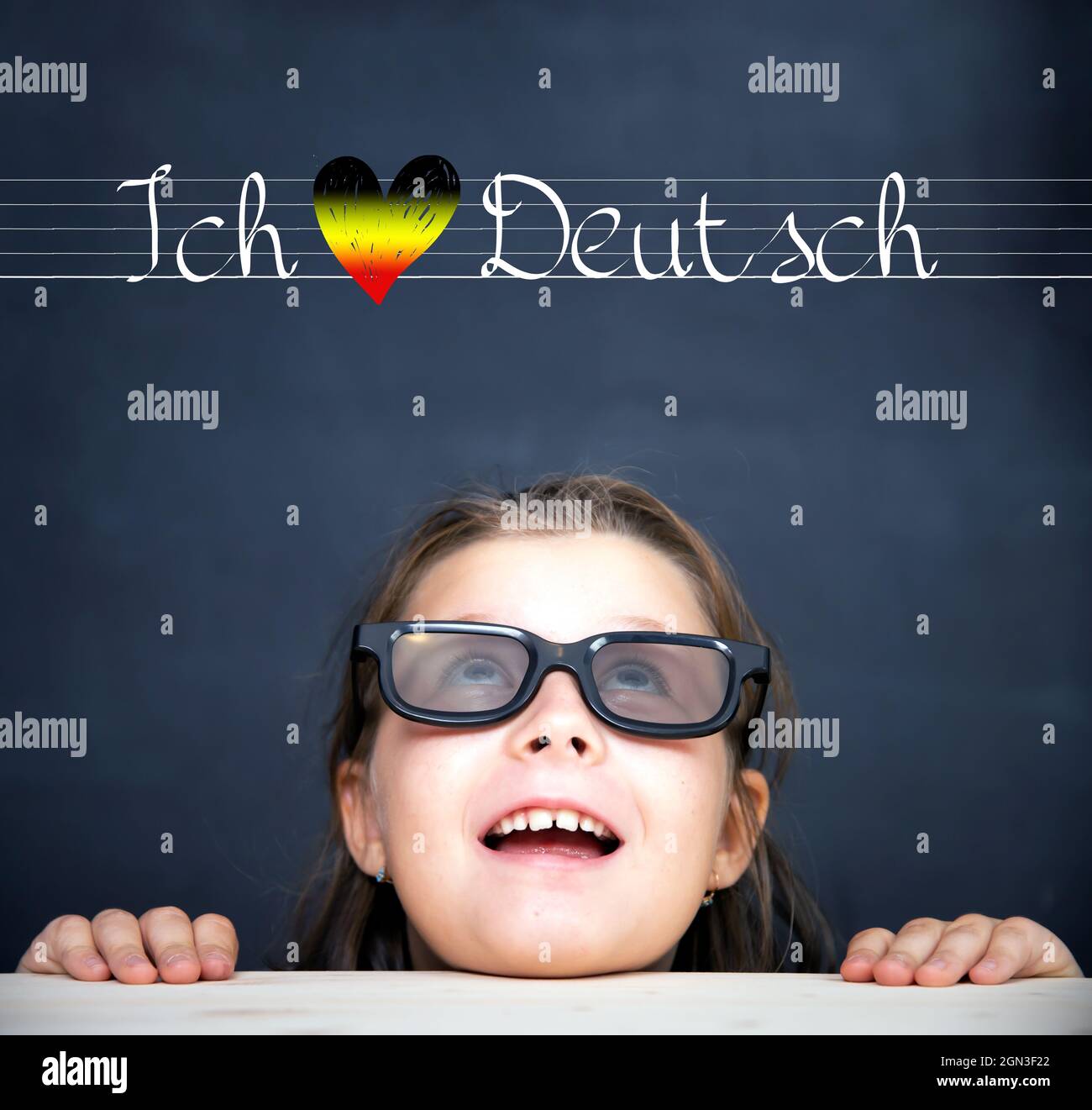 Language education, learn english concept. Little girl with eyeglasses  looking at I love Deutsch text above her Stock Photo - Alamy