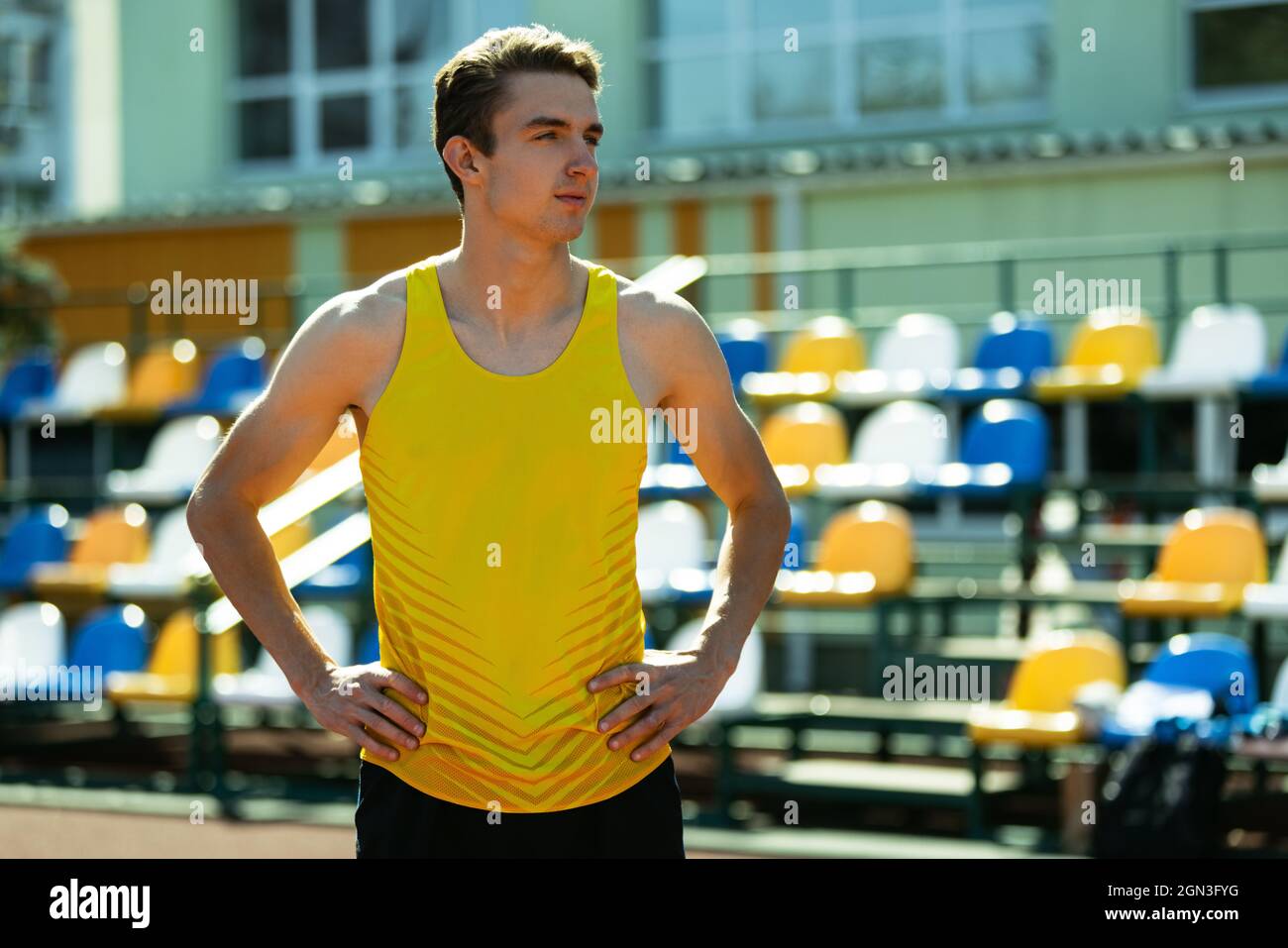 Close-up young Caucasian man, male athlete, runner at public stadium, sport court or running track outdoors. Summer sport games. Stock Photo