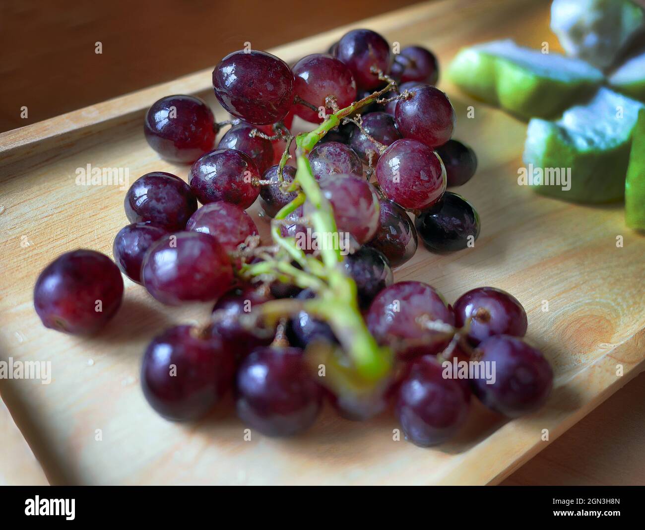 tasty sweet fresh bunch of deep red grapes on wooden tray Stock Photo