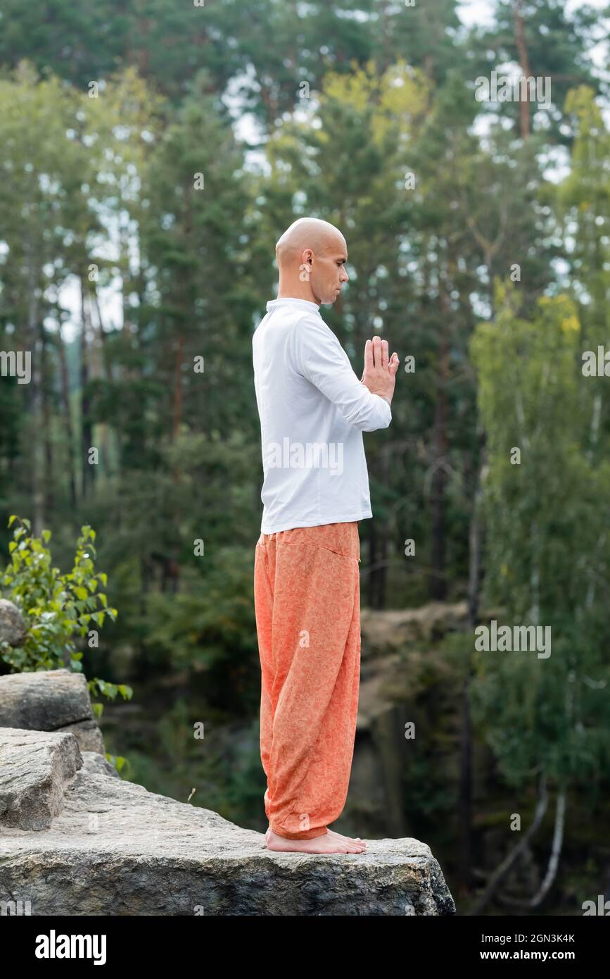 full length view of buddhist in sweatshirt and harem pants practicing yoga  in one legged tree pose Stock Photo - Alamy