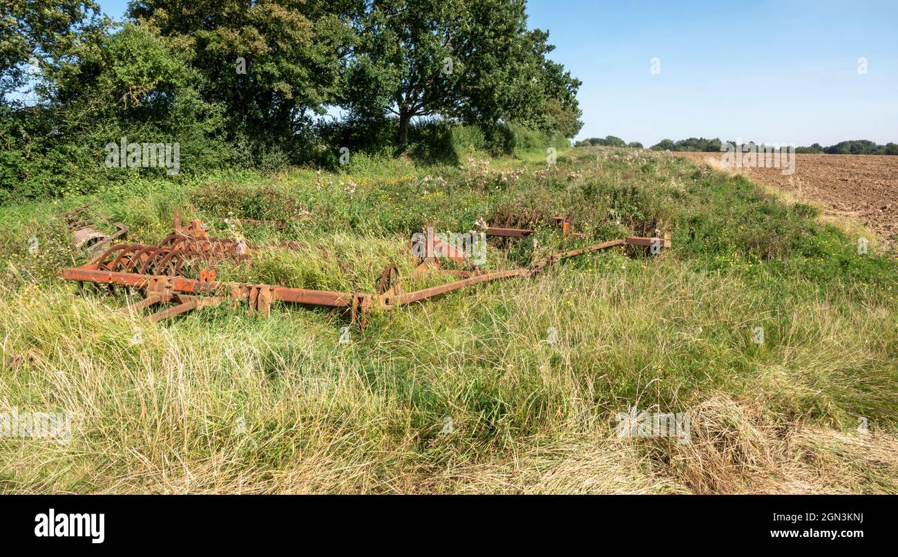 Heavy farming equipment parked on a grassy field boundary Stock Photo