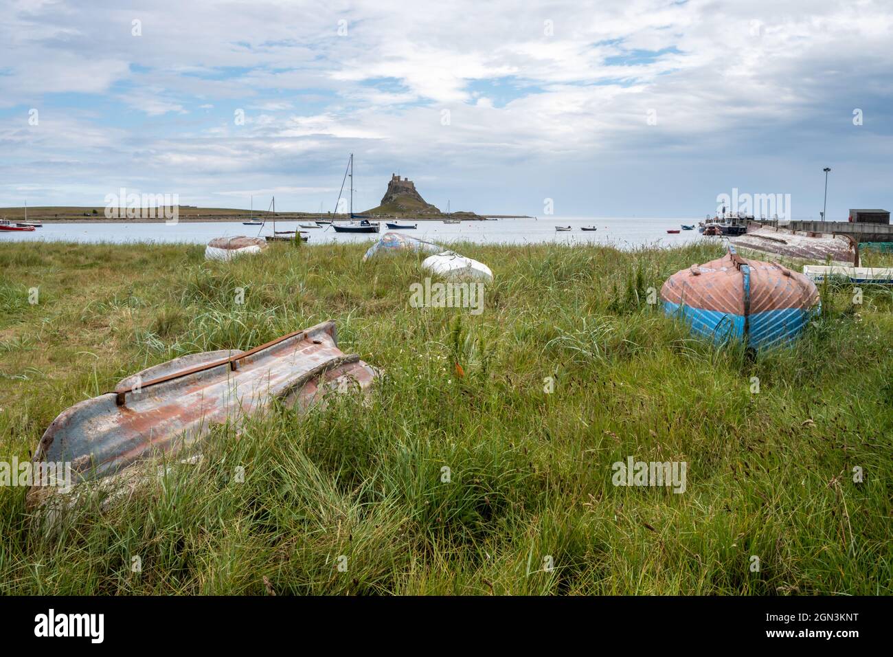 Upturned boats around the harbour on Lindisfarne looking across to the castle Stock Photo