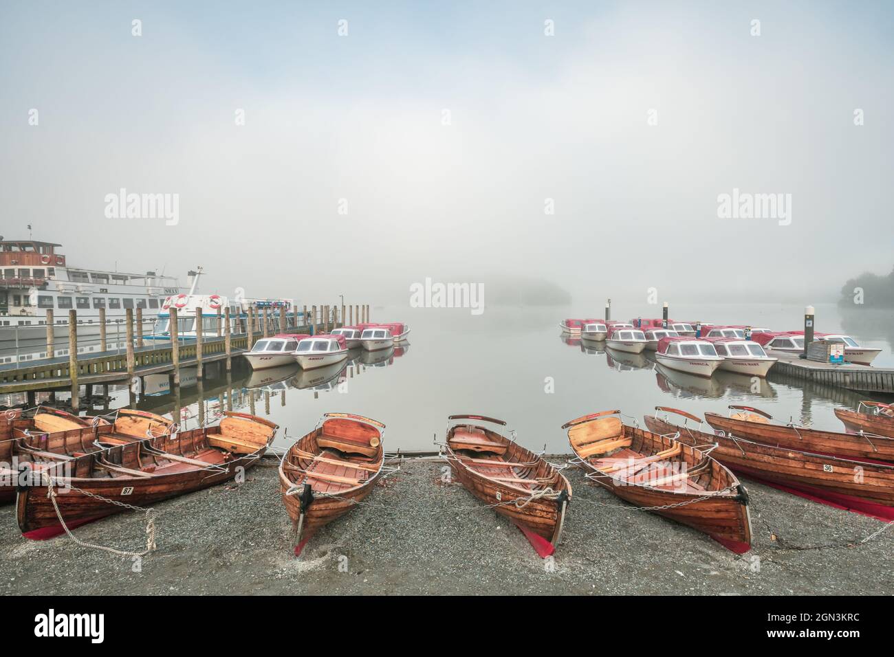 Rowing boats and motor boats on Windermere on a misty autumn morning Stock Photo