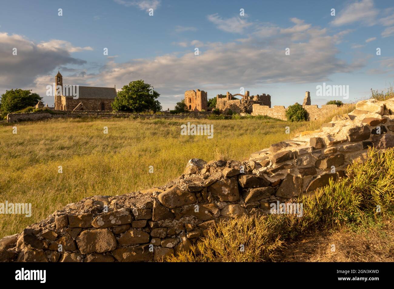 St.Mary's church and the ruins of Lindisfarne Priory in the low evening sunshine Stock Photo