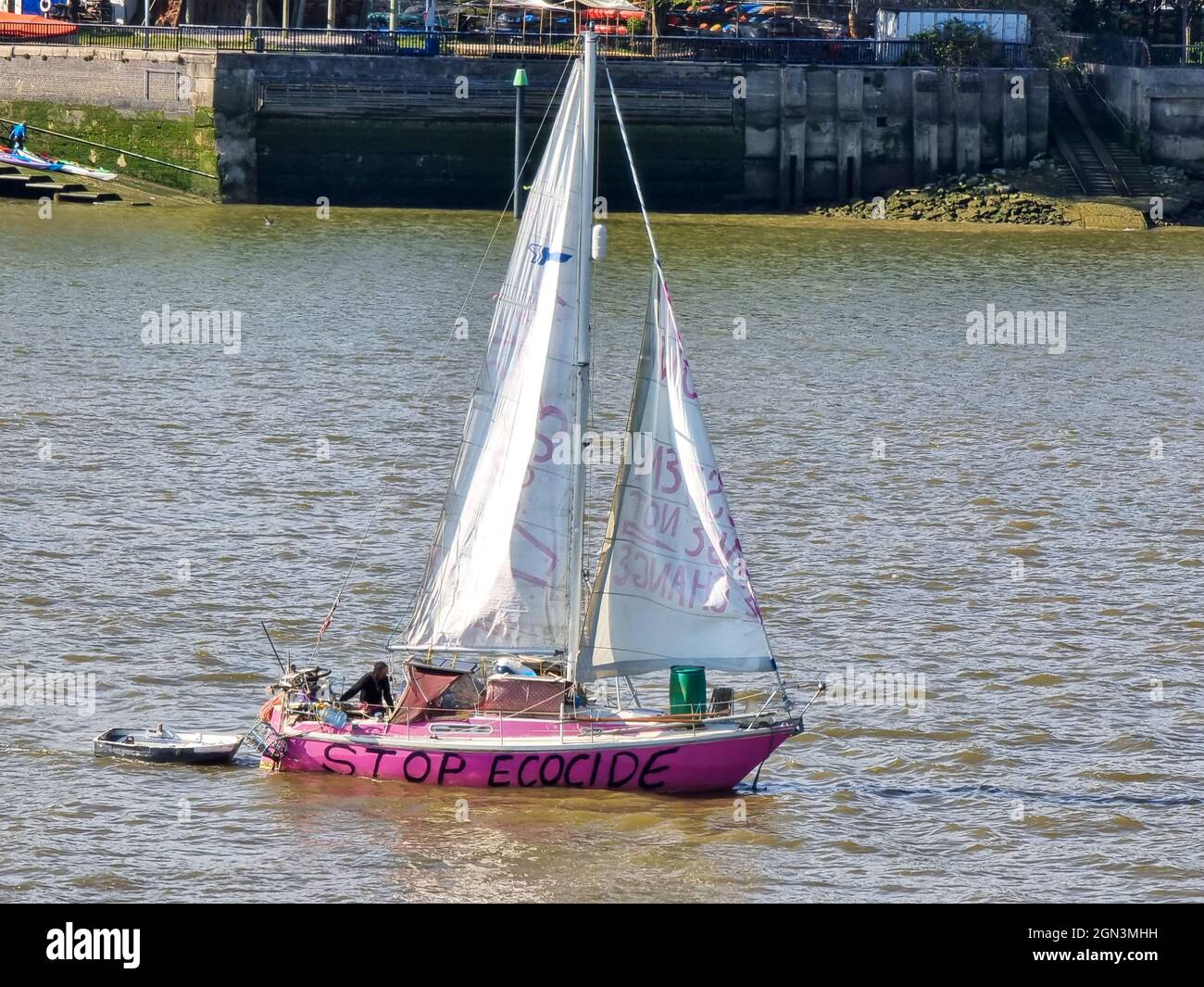 A pink sail boat adorned with environmental messages such as stop ecocide Stock Photo