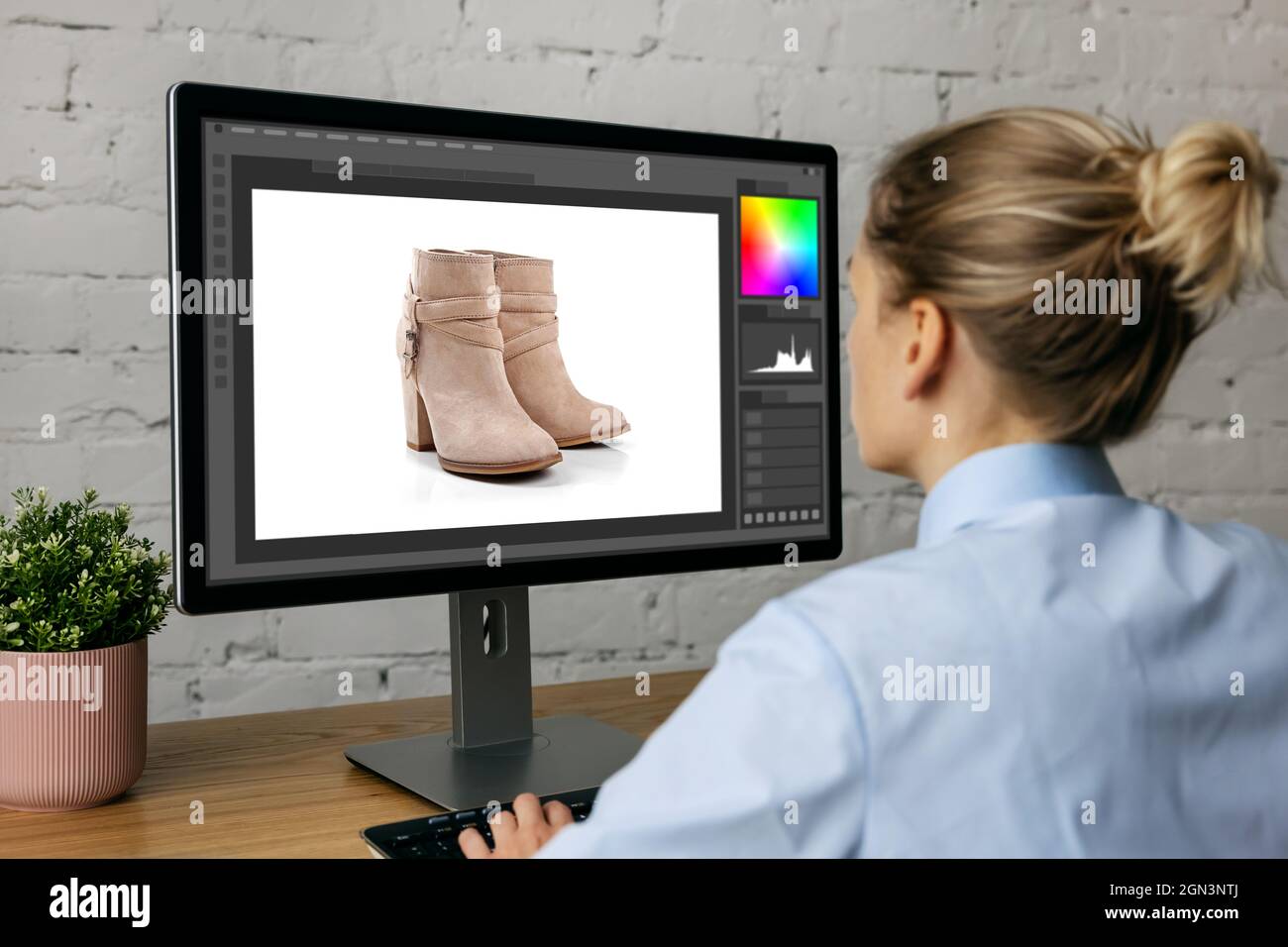 woman doing product photo editing on desktop computer in office Stock Photo