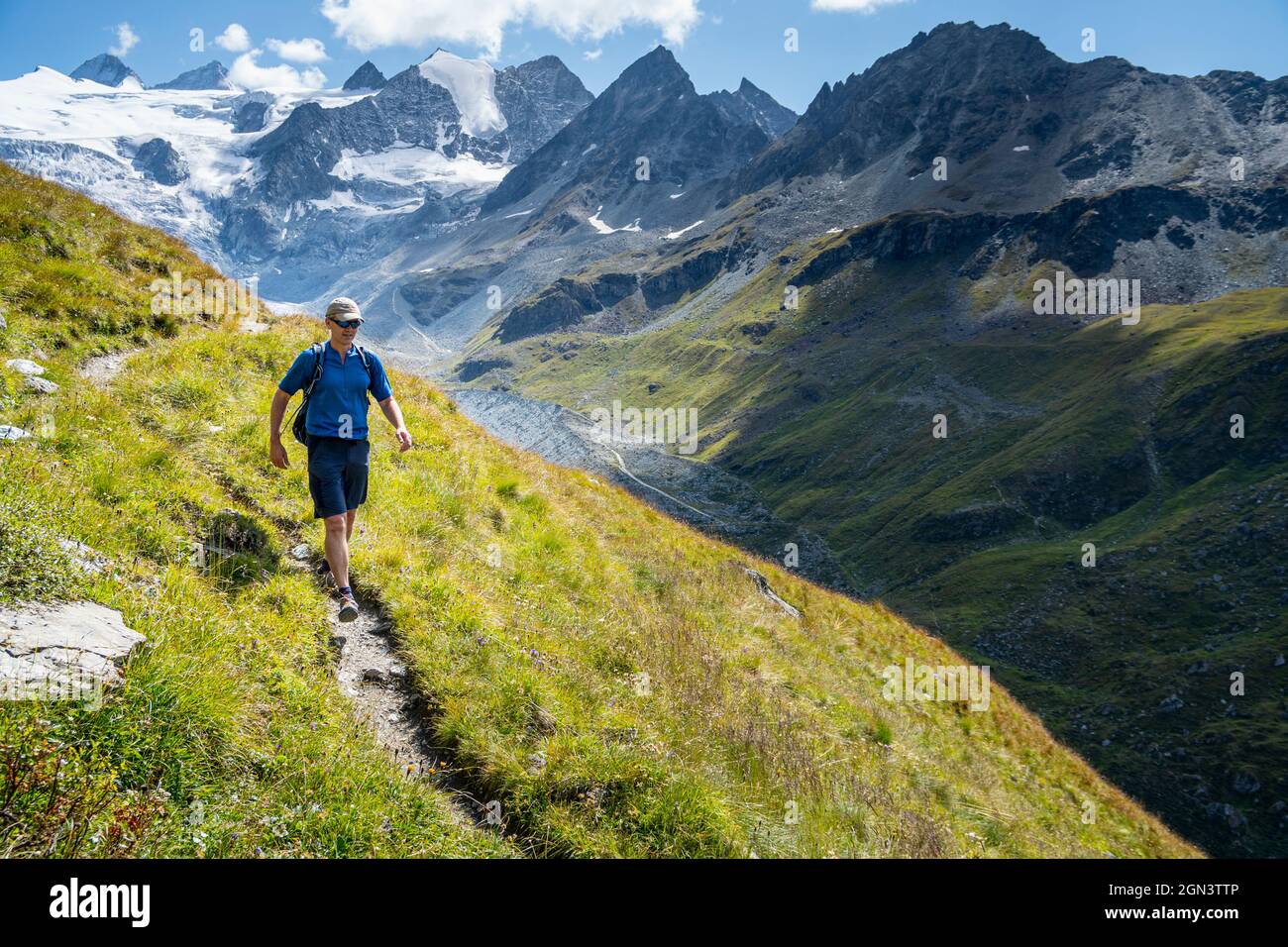 A single male hiker strides out across the Swiss mountains with glaciers in the background. Moiry Valley, Grimentz, Valais Switzerland Stock Photo