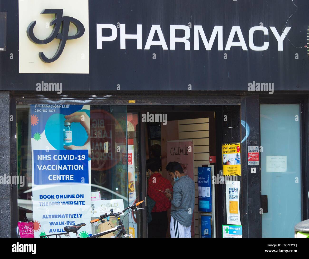 A poster of NHS (National Health Service) Covid-19 vaccination centre is seen outside a pharmacy in London. Stock Photo