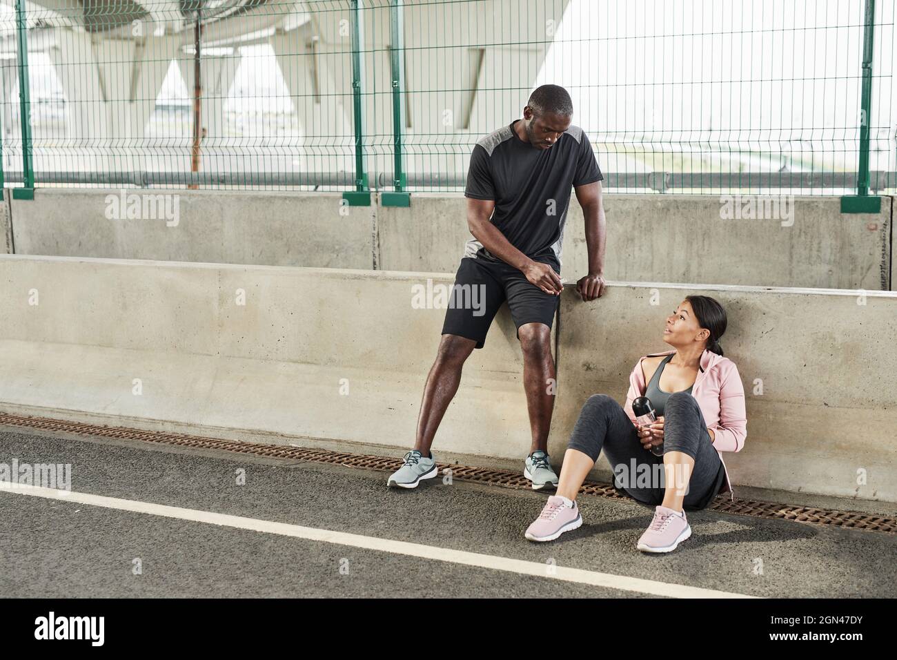 Young couple discussing exercises with each other during their training on the stadium Stock Photo