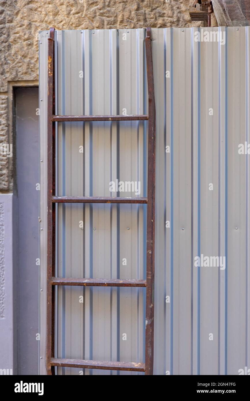 Metal Ladder for Scaffoldings at Construction Site Fence Stock Photo