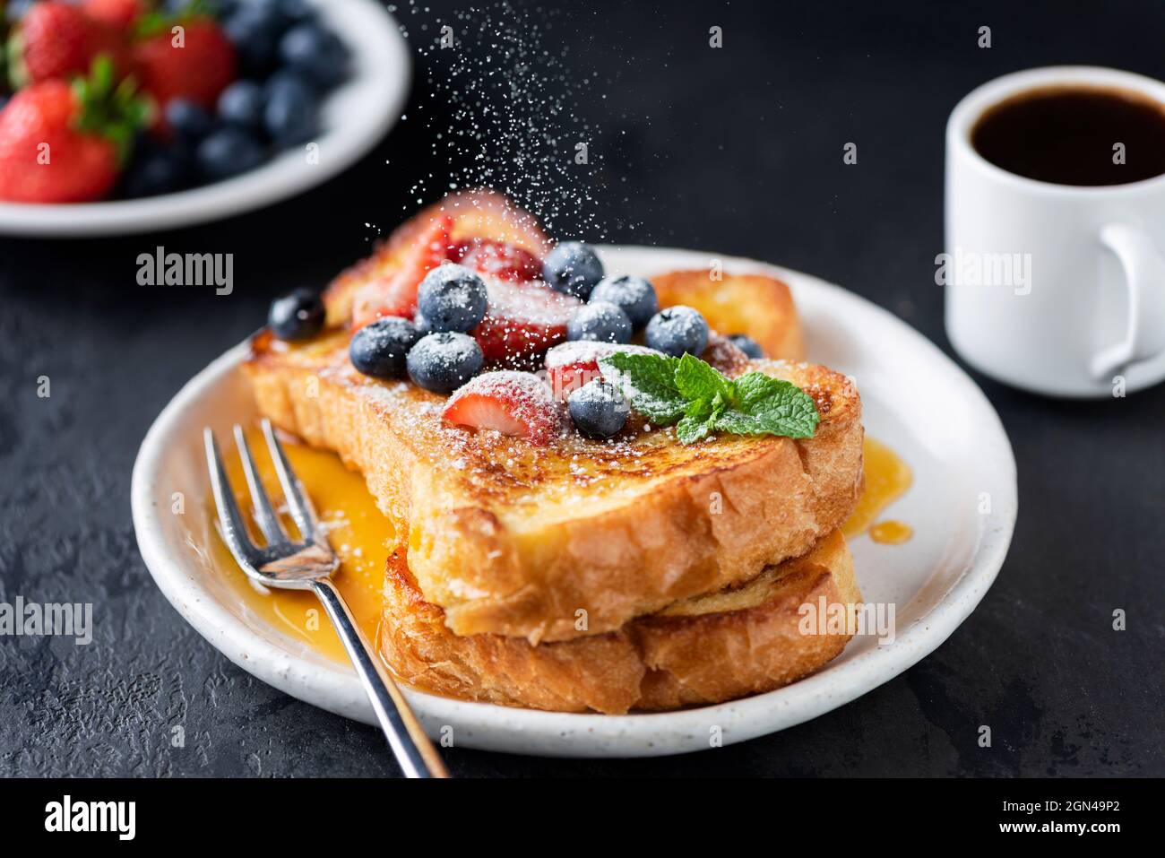 French toast with berries and sugar powder on black concrete background, closeup view. Sweet breakfast food Stock Photo
