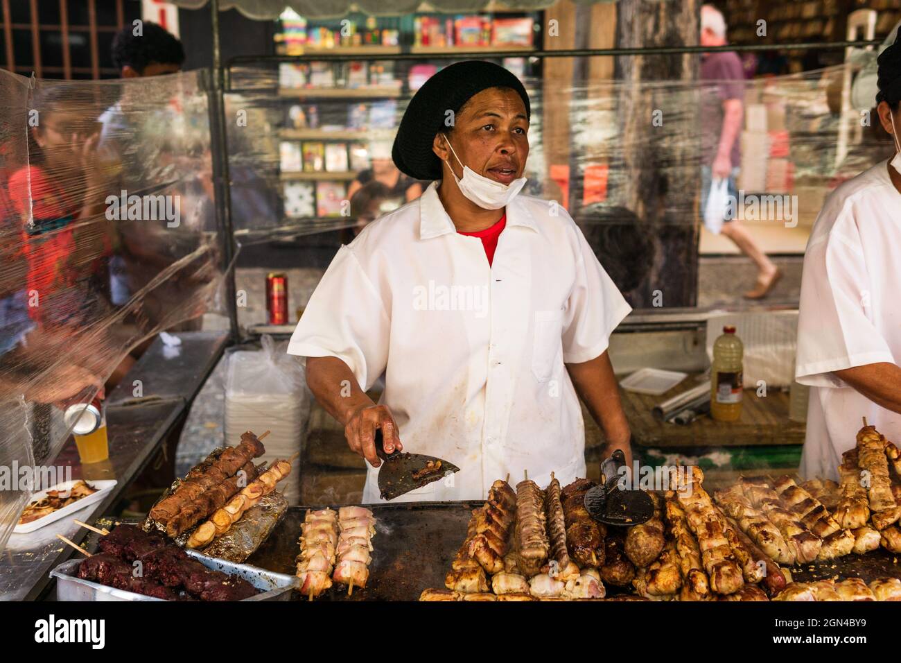 Black woman cooking and steaks, pork chops, and chicken on sticks at the Belo Horizonte Hippie Fair in Brazil. Stock Photo