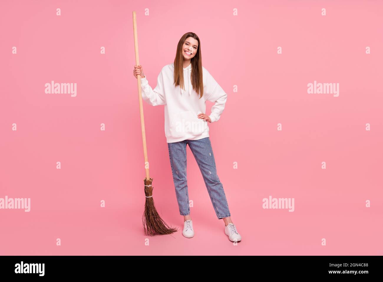 Full size photo of brown hairdo young lady clean wear hoodie jeans sneakers isolated on pink background Stock Photo