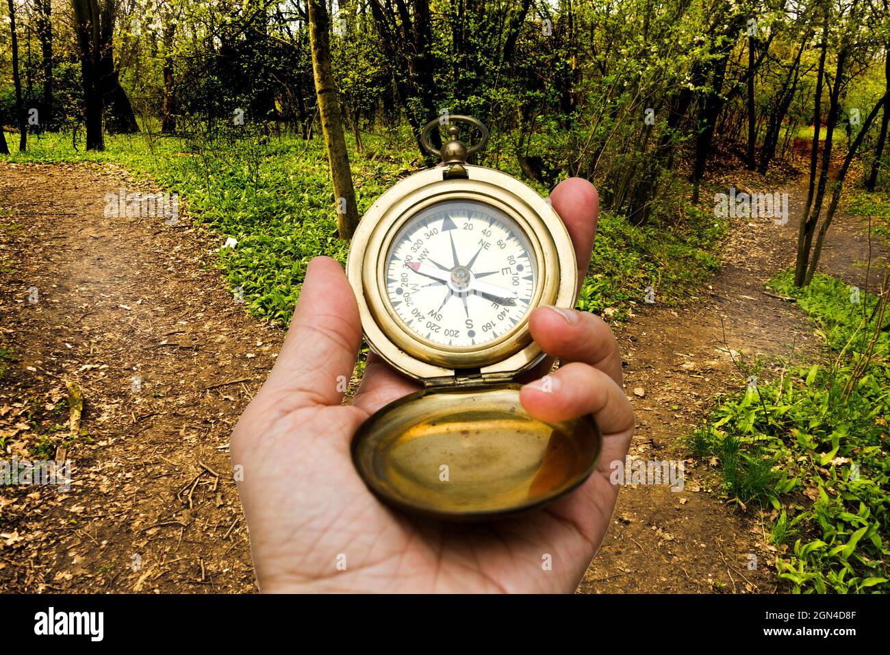 hand holding a compass in front of a crossroad, choosing a direction ...