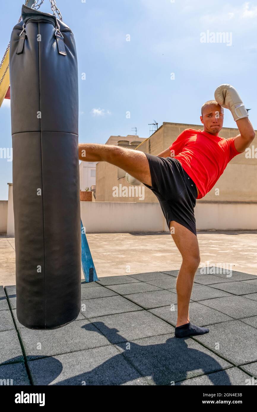Muscular man punching with leg a boxing bag on cross fit training at the  street. Training concept Stock Photo - Alamy