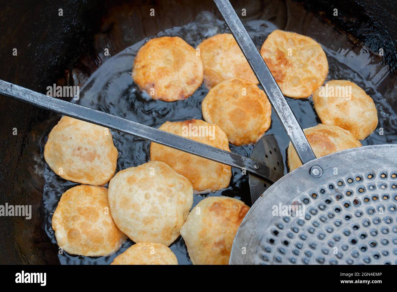Kochuris are being fried in a frying pan. Kochuri, kachori of kachauri is a spicy snack, fried dumpling and a very popular street food in India. Stock Photo