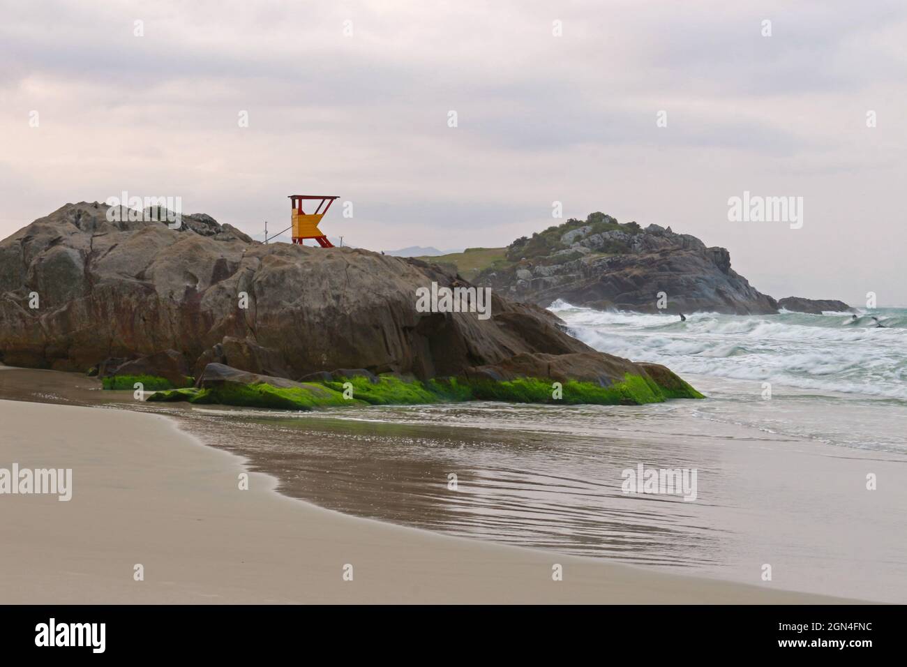 Of a beach formed by an inlet of the sea. Rocks and darker sand and the sighting of a lifeguard house Stock Photo