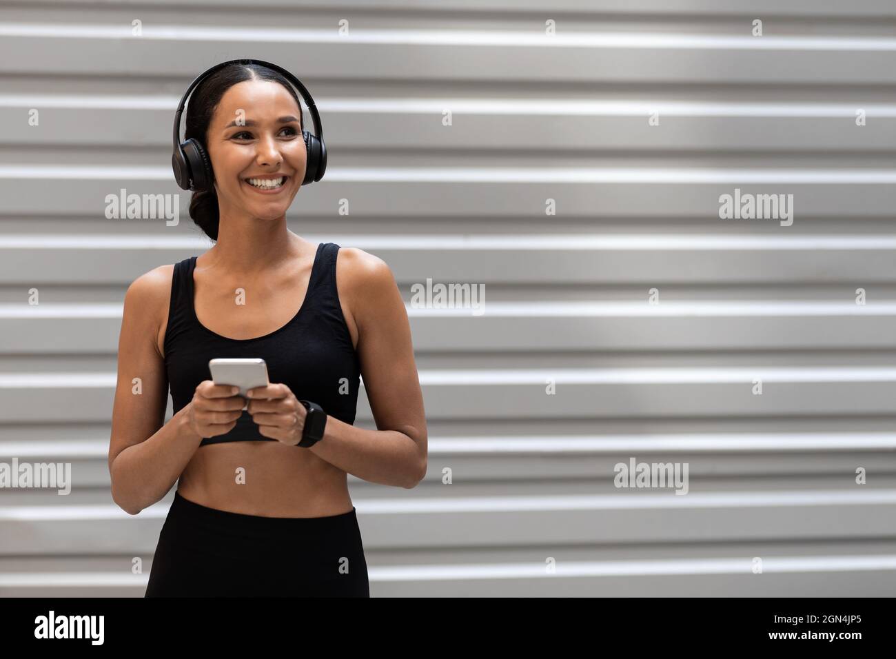 Woman In Sportswear And Wireless Headphones Resting With Smartphone After  Training Outdoors Stock Photo - Alamy
