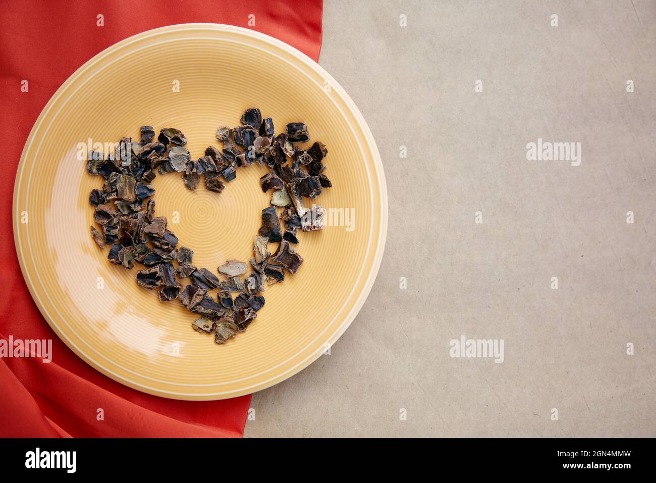 Carob in shape of heart symbol of coffee alternative - natural product on the plate. Organic plant-based caffeine antioxidants. Top view, copy space. High quality photo Stock Photo