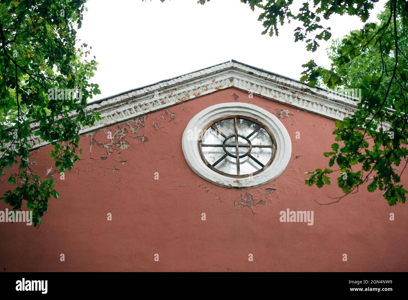 Round window under a roof in a red house facade Stock Photo