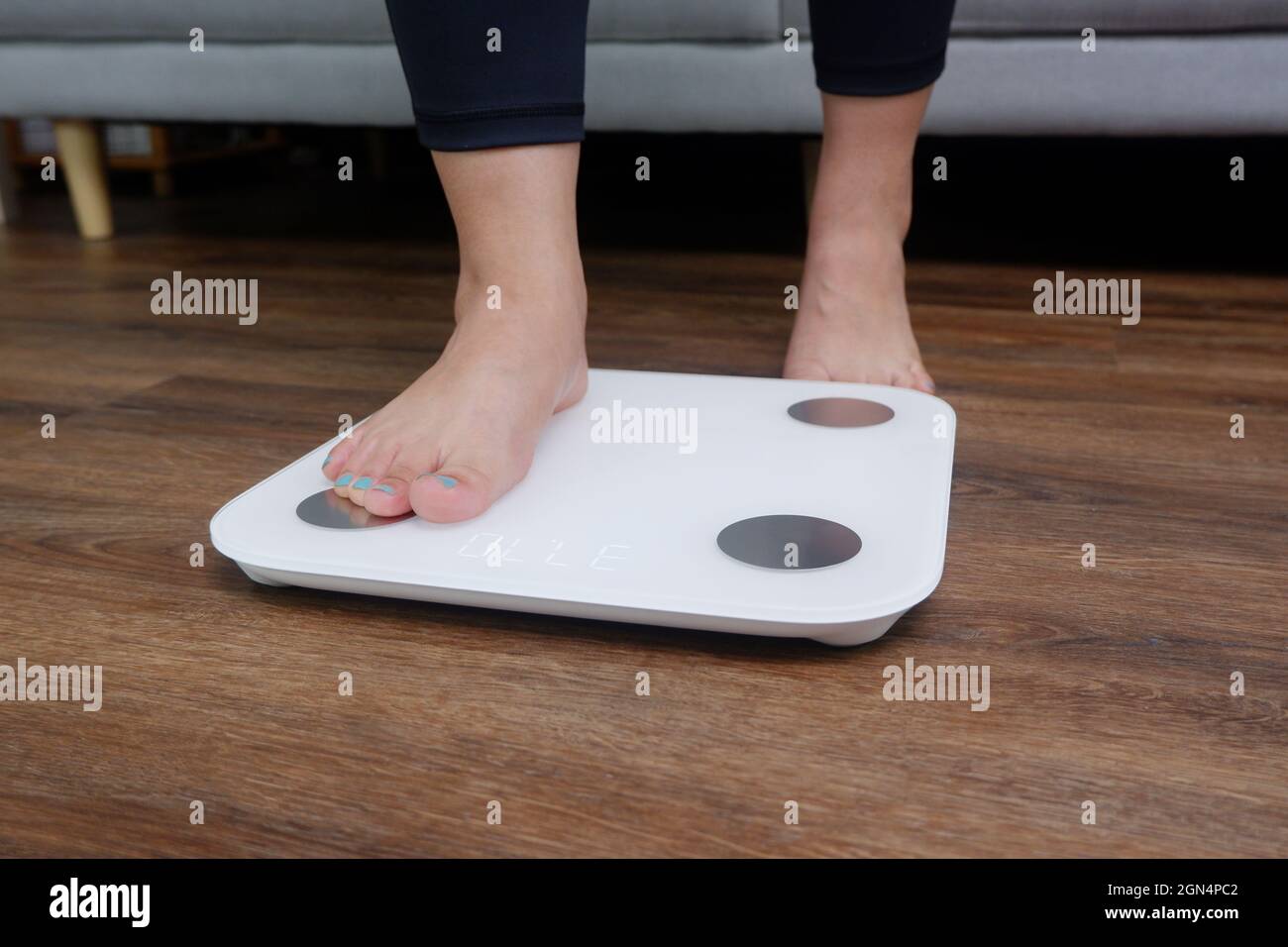 Closeup female feet stepping on body weight scale. Weight control