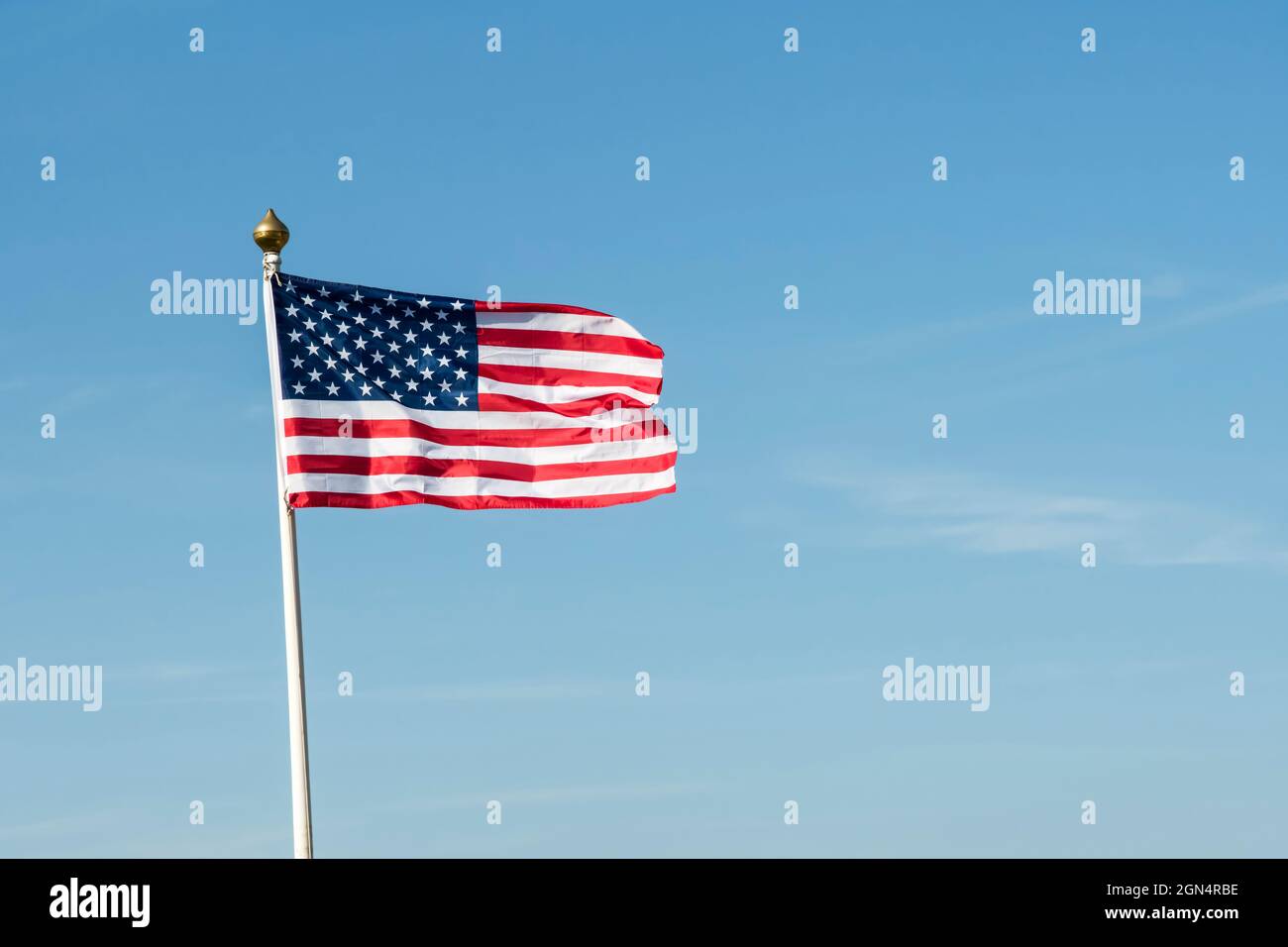 The American flag or stars and stripes flying against a blue sky.  See 2GN4RC4 for cutout version. Stock Photo