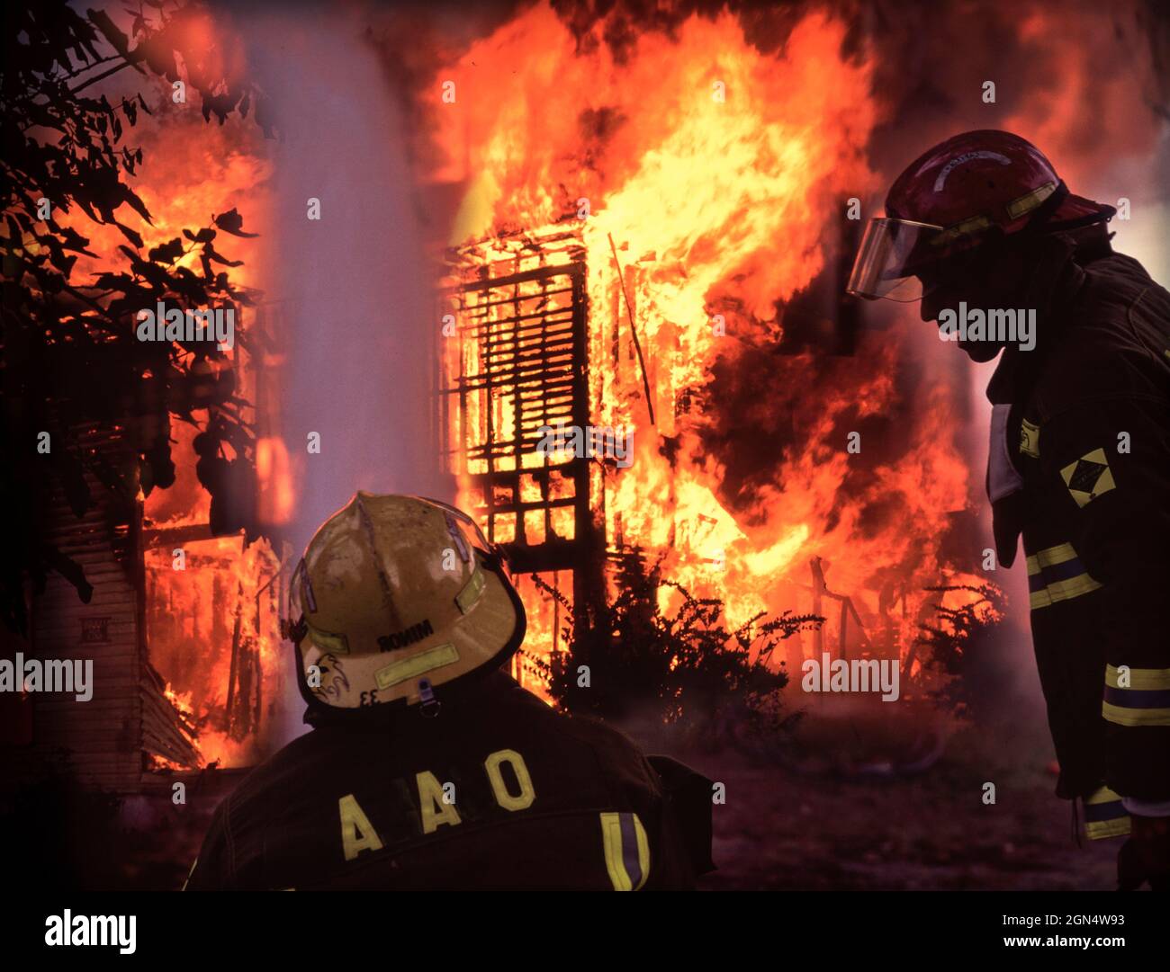 Firemen spraying water on burning house fire Stock Photo