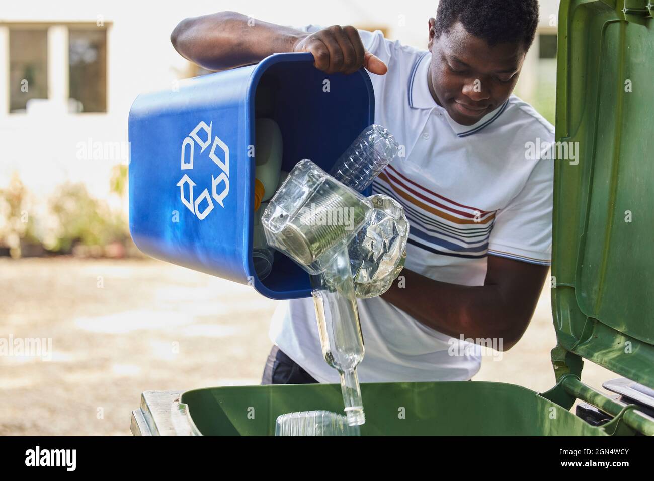 Young Man Emptying Household Recycling Into Green Bin Stock Photo Alamy