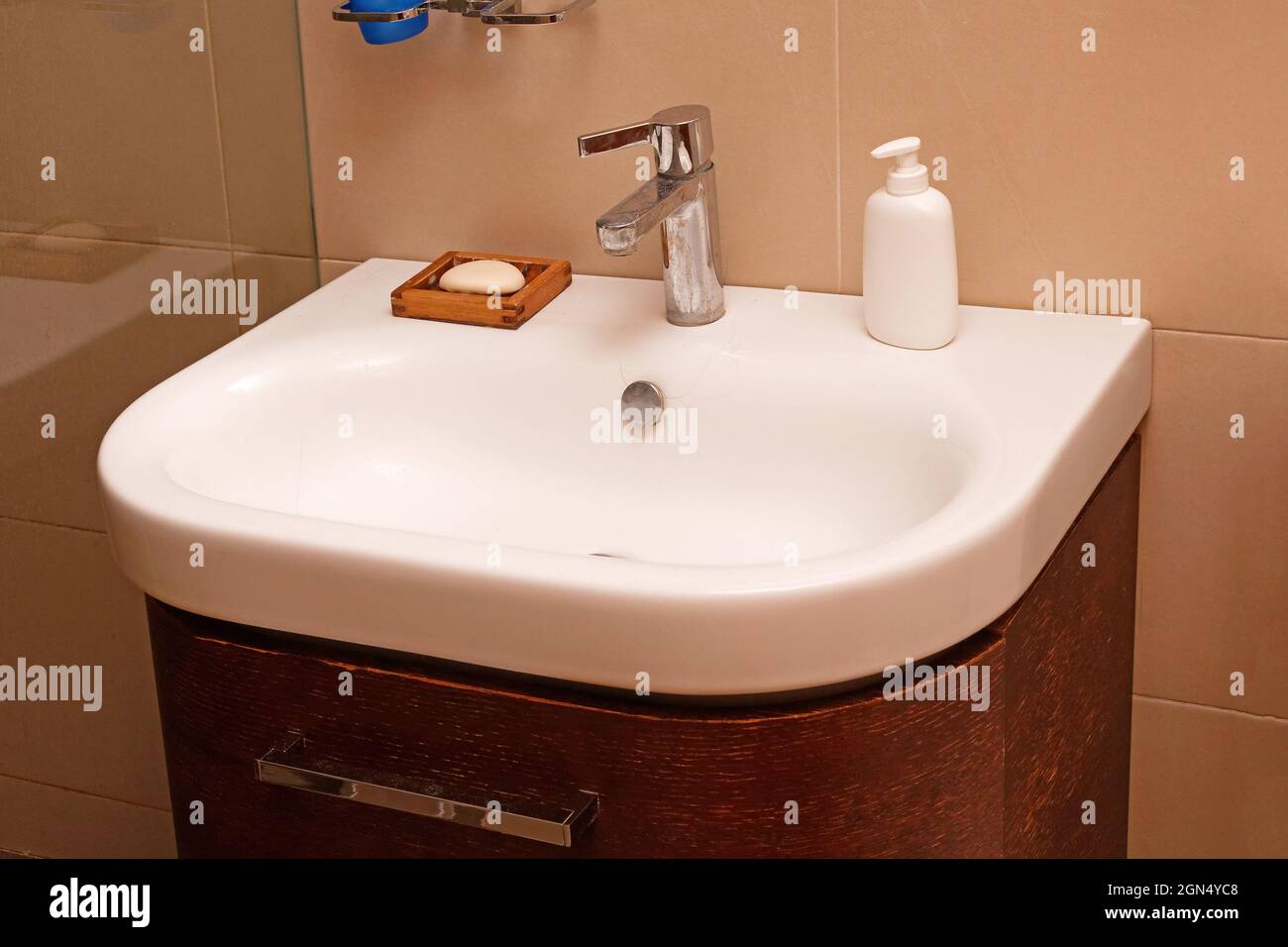 Modern white ceramic bathroom sink with silver tap and soap on wooden