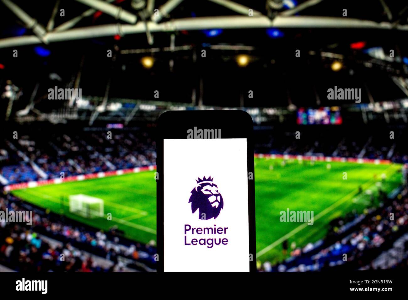 In this photo illustration a Premier League logo seen displayed on a smartphone with a soccer stadium in the background. Stock Photo