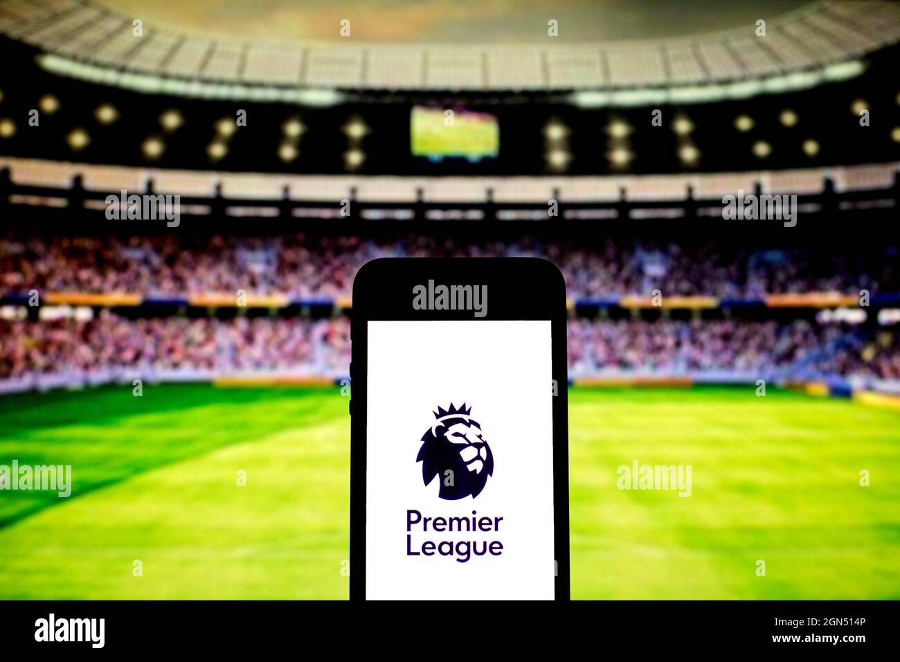 In this photo illustration a Premier League logo seen displayed on a smartphone with a soccer stadium in the background. Stock Photo
