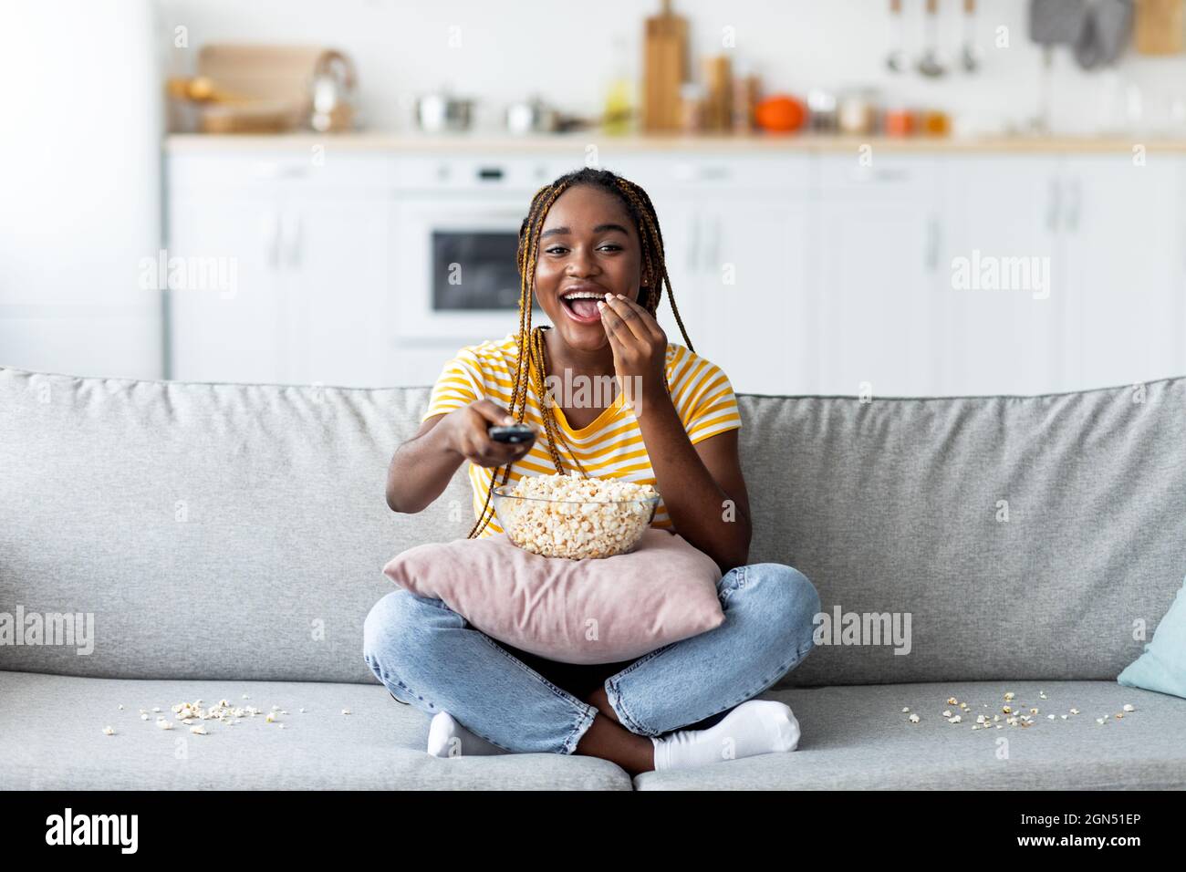 Laughing young black woman watching TV at home Stock Photo