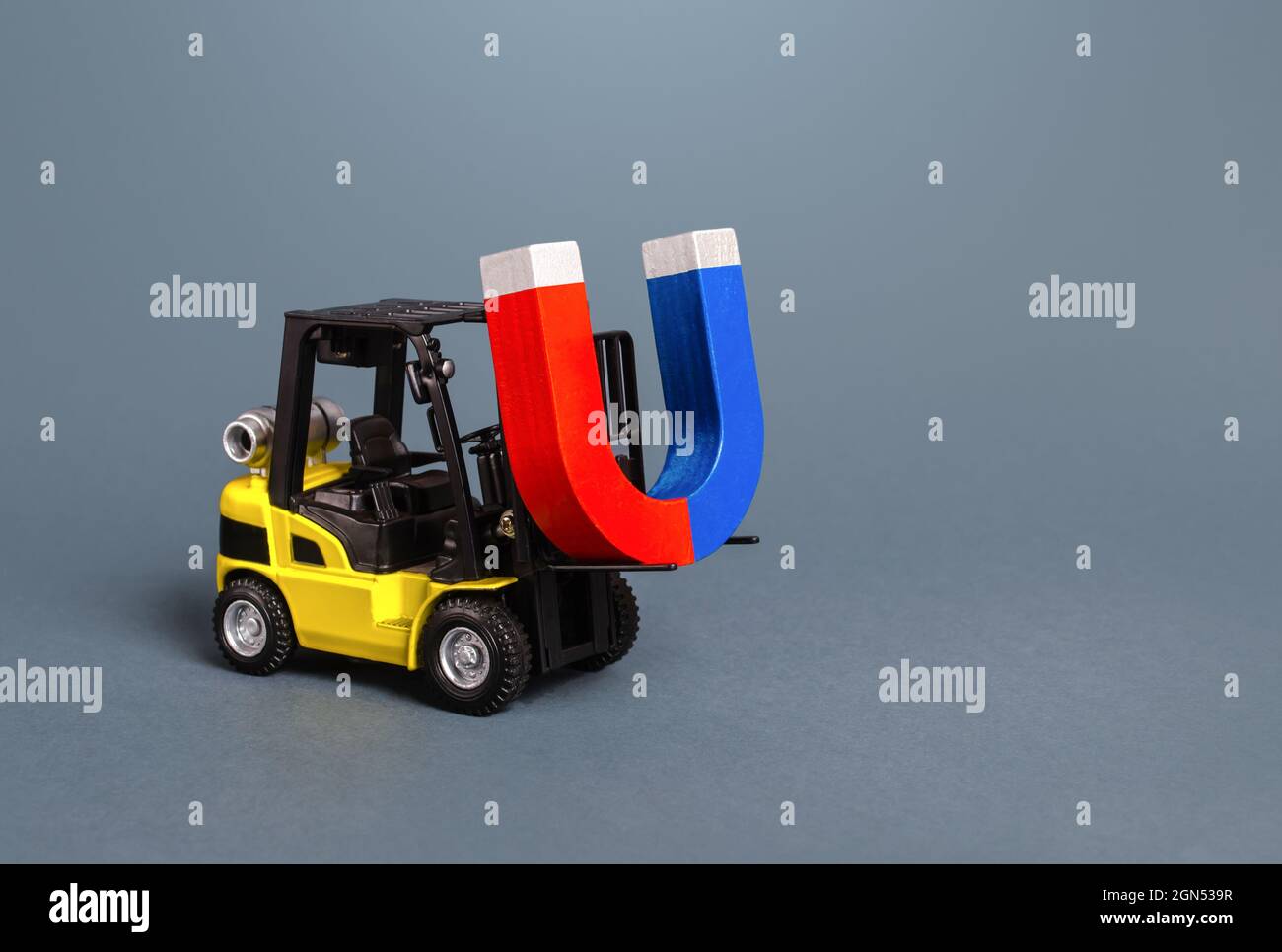 A forklift is carrying a big magnet. The concept of attraction and gravity. Attracting money and investments for startups. Increase profits and attrac Stock Photo
