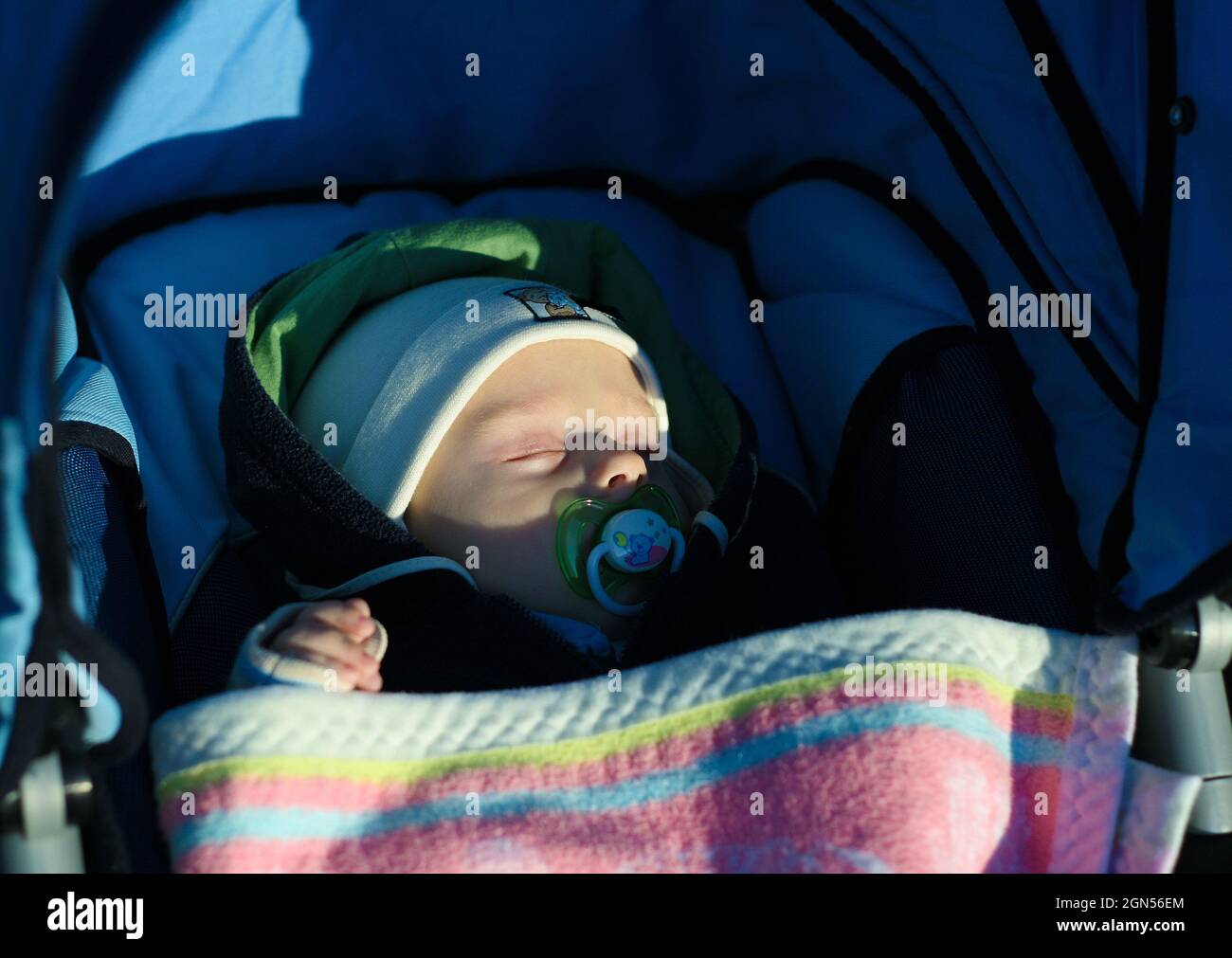 Five months old baby boy sleep with pacifier in stroller on the walk