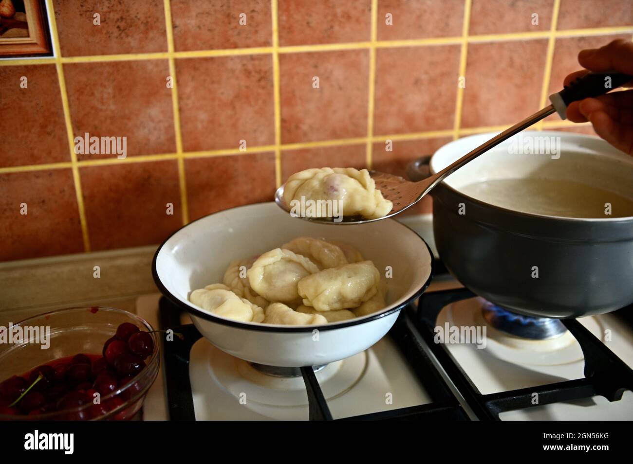 The pastry chef takes out cooked dumplings from boiling water into a