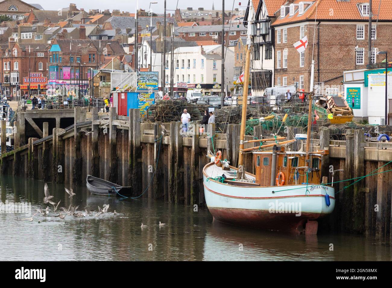 Scarborough Harbour, A fishing boat is moored up as Gulls dive in for Fish. Stock Photo