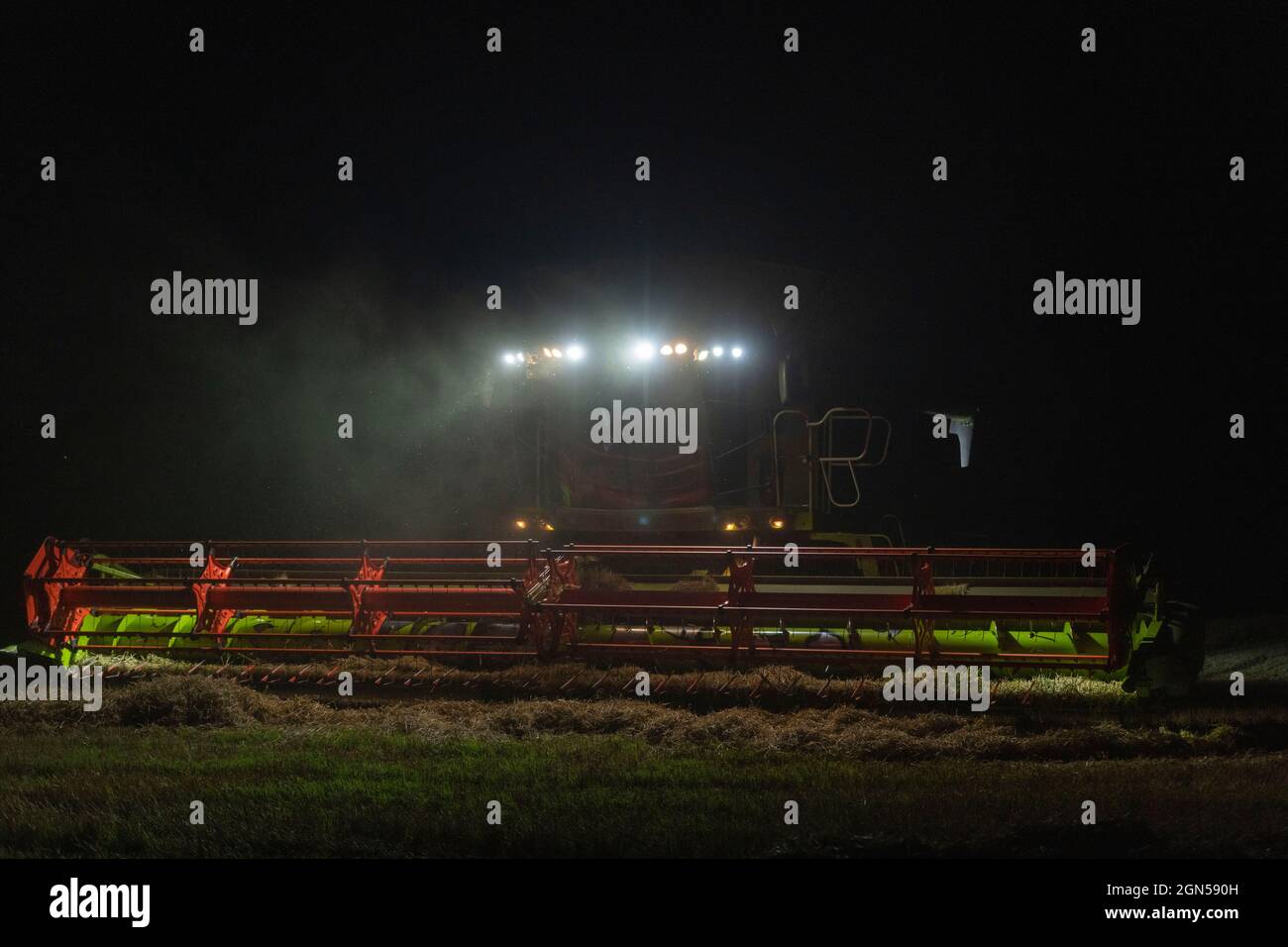 A Combine Harvester Working Late into the Evening on a Scottish Farm Stock Photo