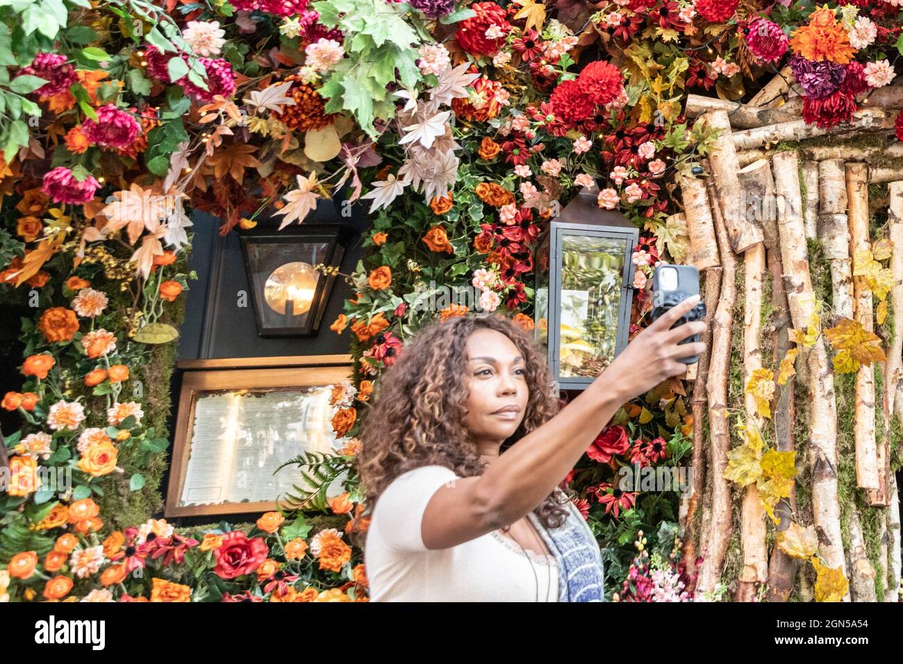 London, UK. 22nd Sep, 2021. A woman takes selfies with the very colourful display at the Ivy restaurant on King´s Road. Chelsea in Bloom is an annual festival and competition of floral and plant displays by participating shops, restaurants and other businesses in Chelsea, this year running Sep 20-25. Credit: Imageplotter/Alamy Live News Stock Photo