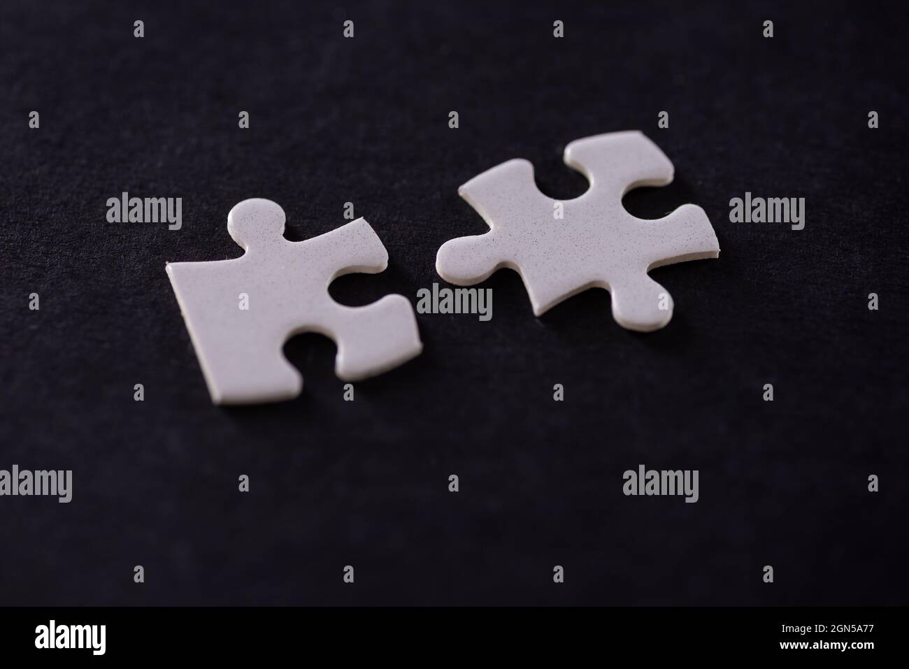 Two white jigsaw puzzles isolated on black background Stock Photo