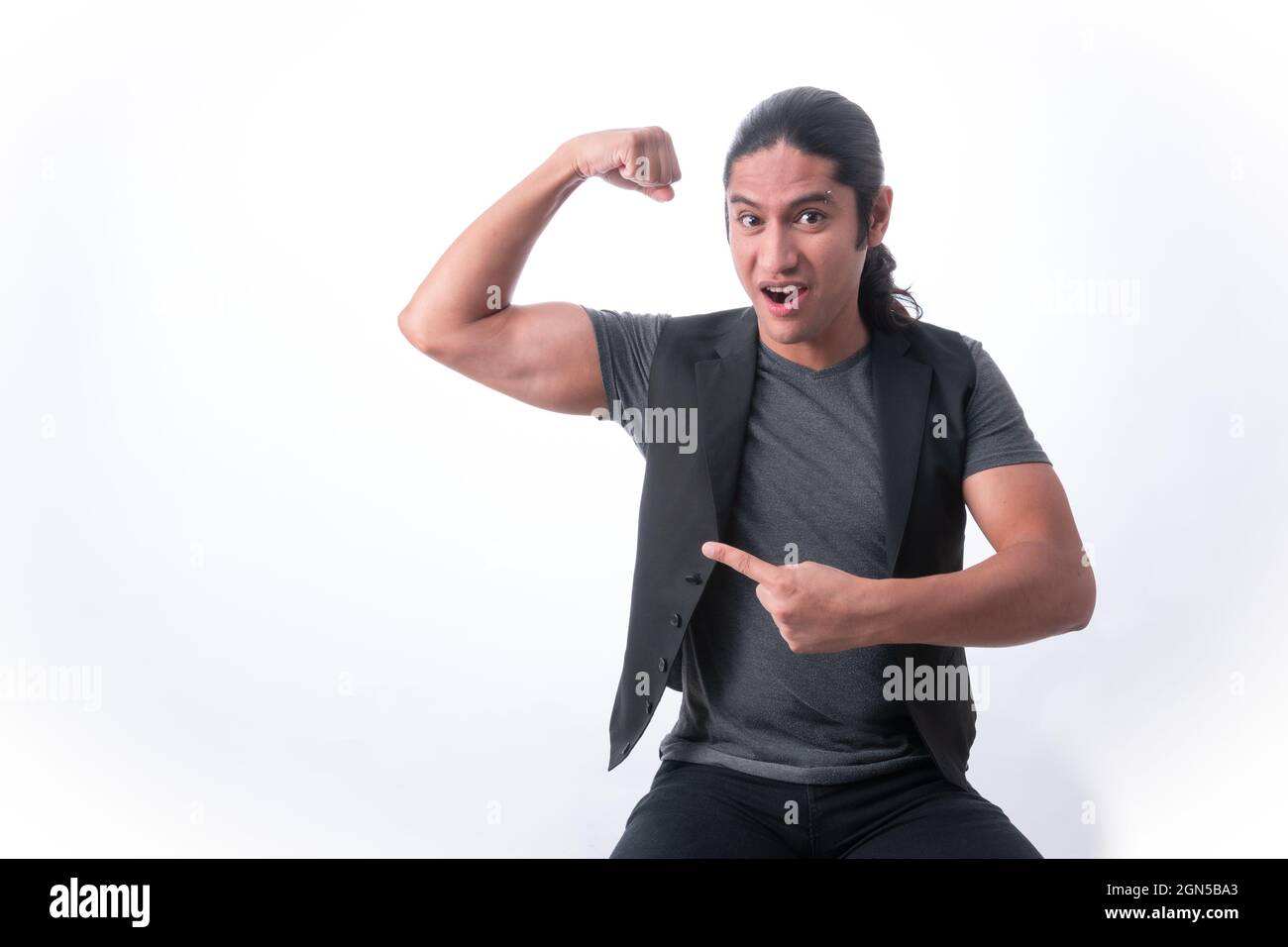 Person with white background. He shows in muscle he has in his arm and with the other hand he points out how strong he is. White space. Man gesticulat Stock Photo