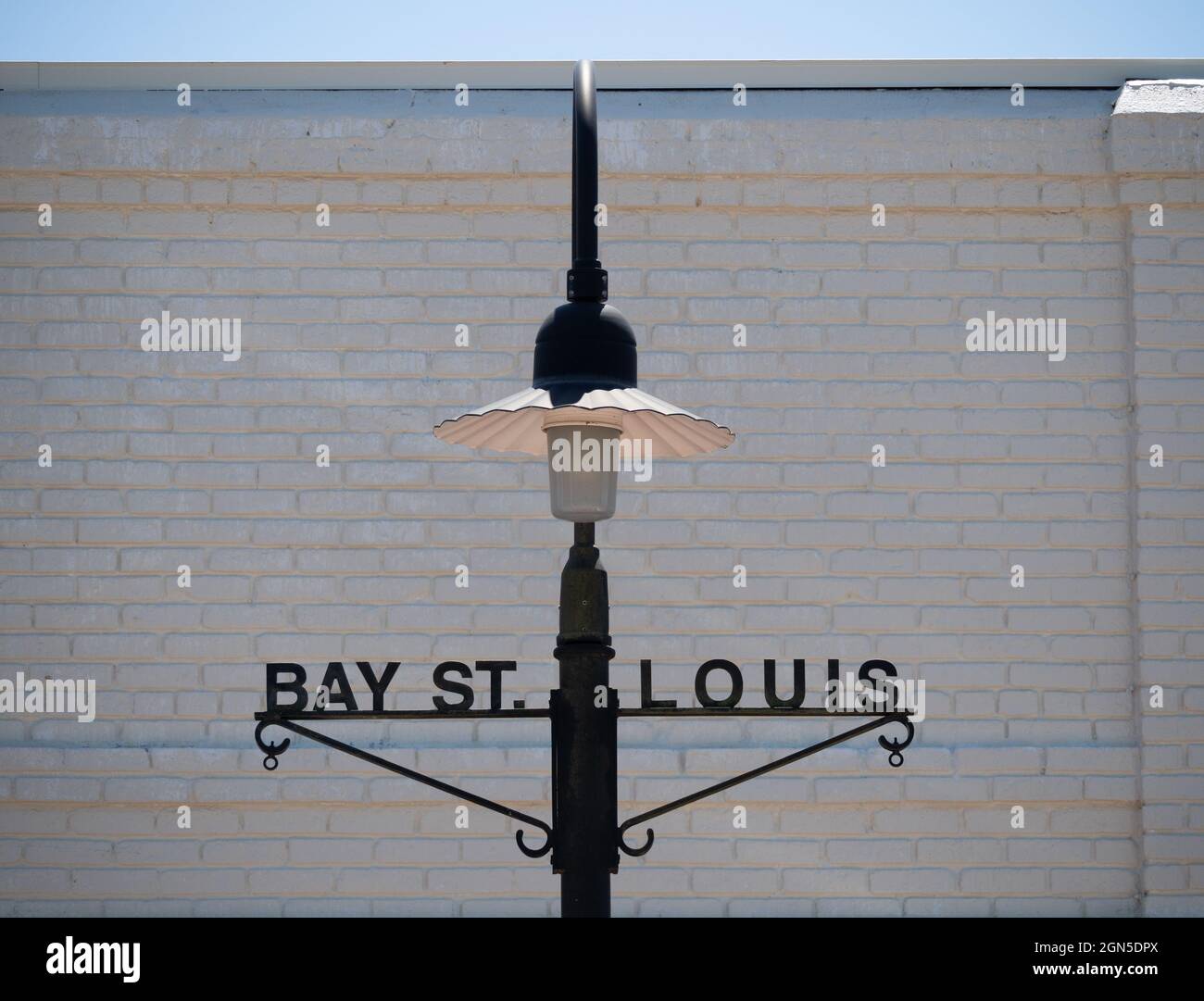 Old fashioned style street lamp in Bay St. Louis, Mississippi photographed with a white brick wall in the background. Stock Photo