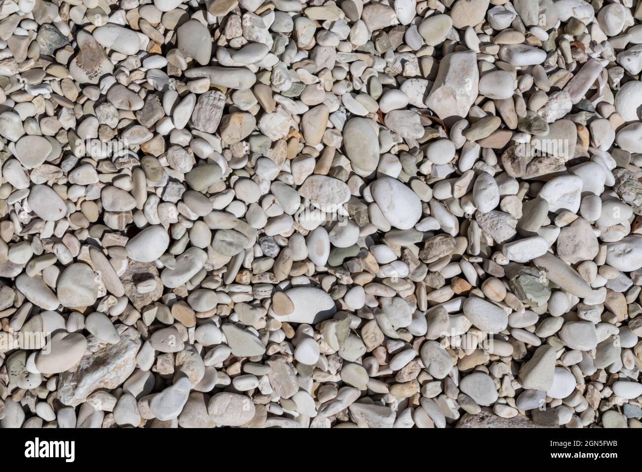 Ionian sea pebble marble stone beach close-up texture. White and beige colors rocks in Greece, Lefkada island coast Stock Photo
