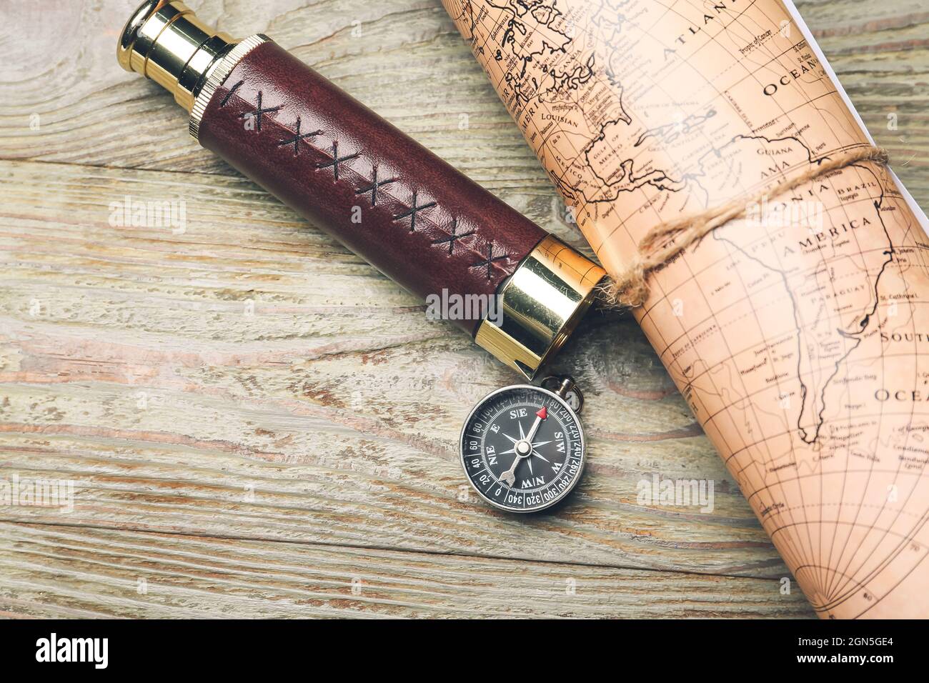 Old spyglass and compass with vintage world map on wooden background ...