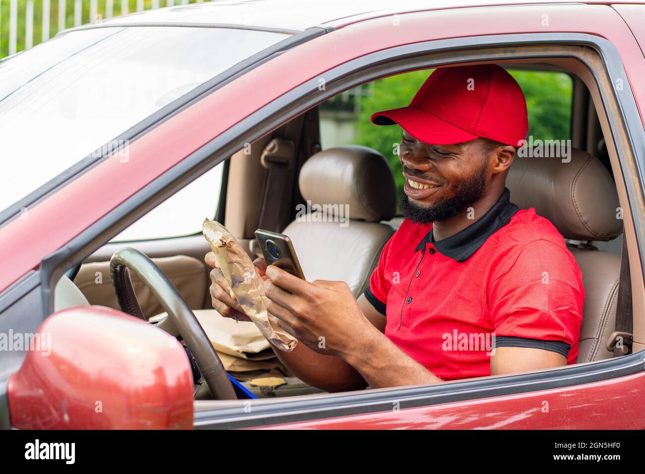delivery worker using his phone, sitting inside a car Stock Photo
