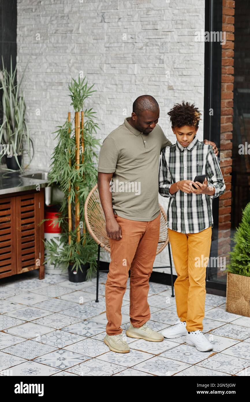 Vertical full length portrait of happy African American grandpa talking ...