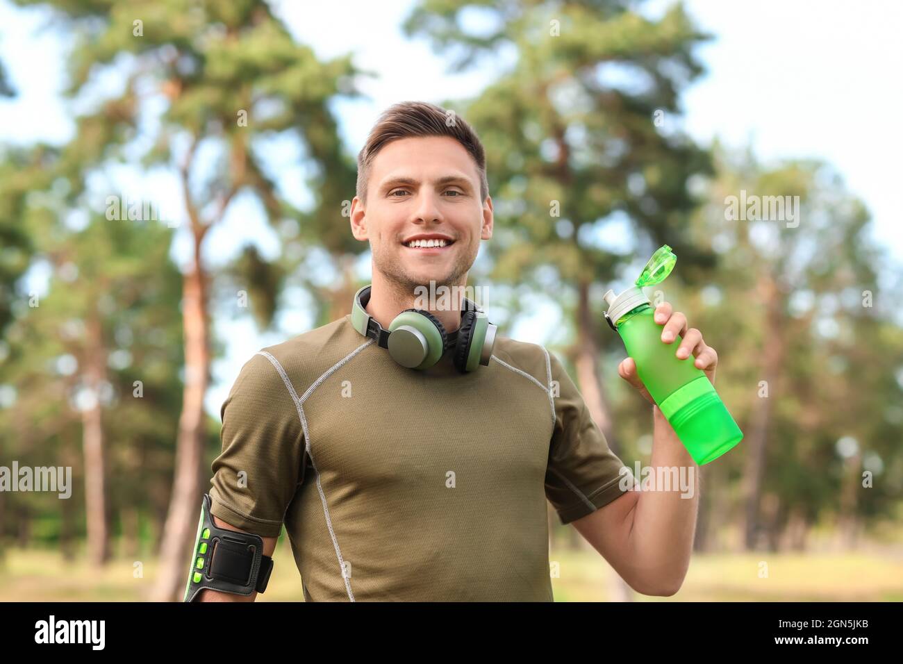 Sporty young man with bottle of water and headphones in park Stock ...