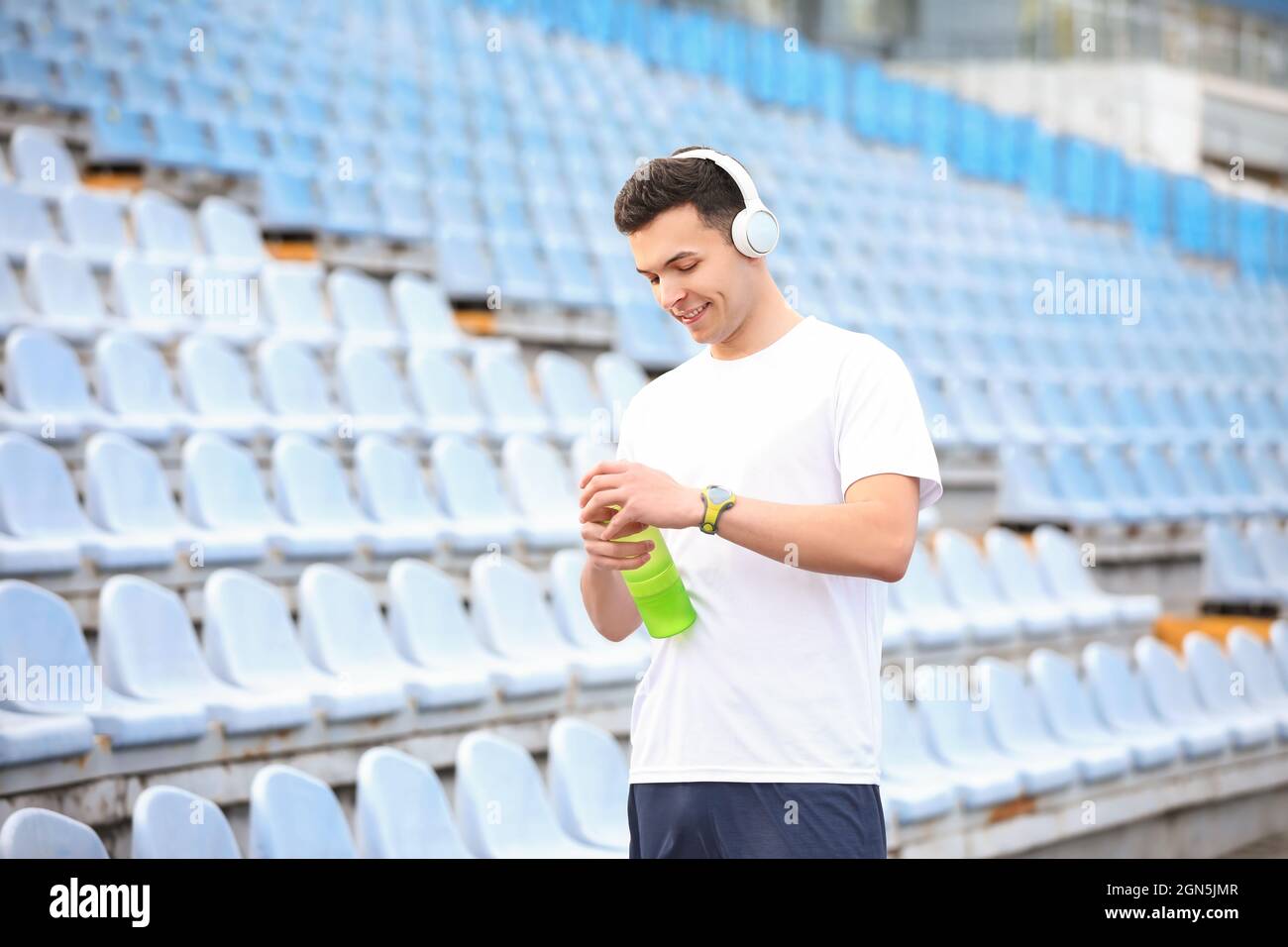 Sporty young man opening bottle of water at stadium Stock Photo - Alamy